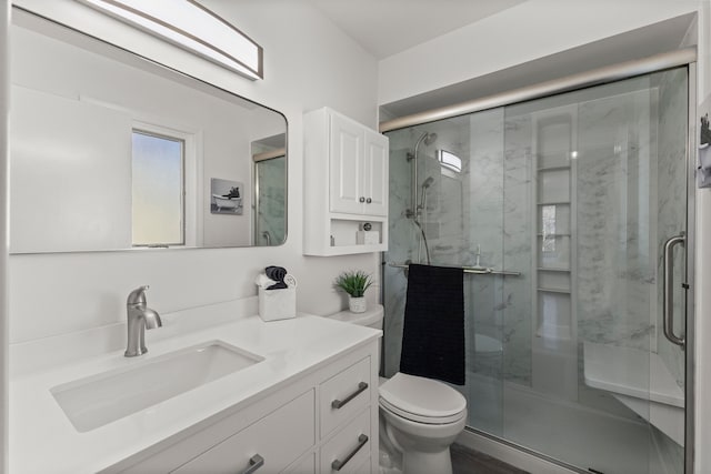 bathroom with vanity, a shower stall, and toilet