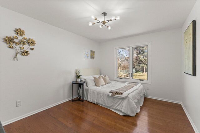 bedroom with an inviting chandelier, baseboards, and wood finished floors