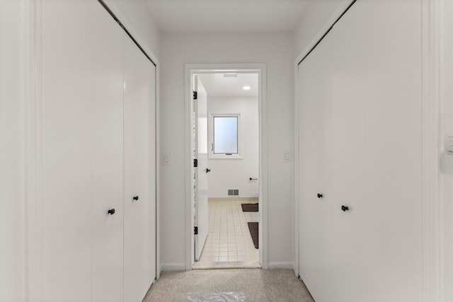 hall featuring light tile patterned floors and visible vents