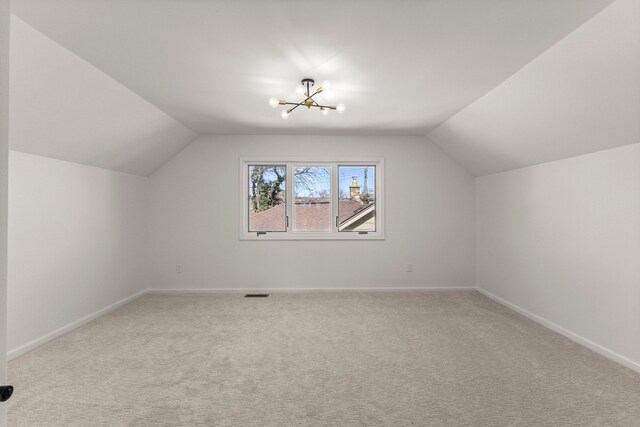 additional living space featuring visible vents, baseboards, lofted ceiling, light carpet, and a notable chandelier