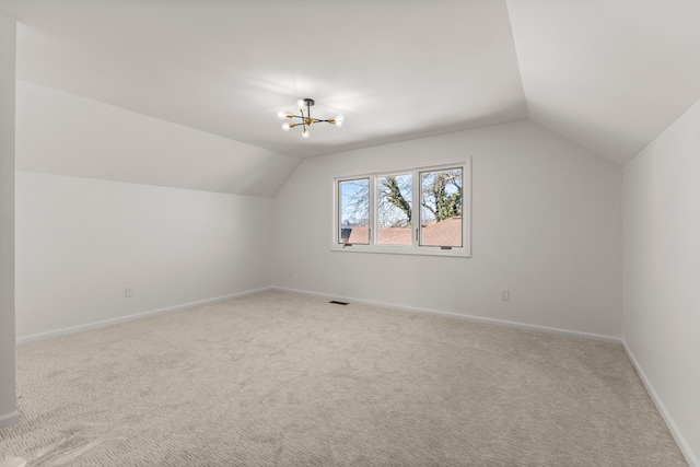 bonus room featuring visible vents, light carpet, a chandelier, and vaulted ceiling