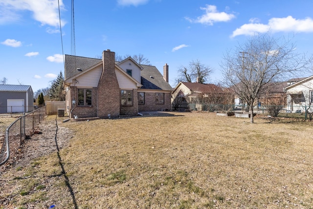 back of house with brick siding, a fenced backyard, and a lawn