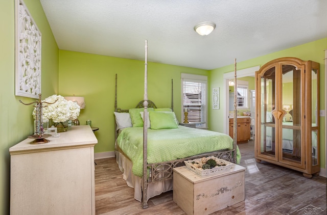 bedroom featuring a textured ceiling, baseboards, and wood finished floors