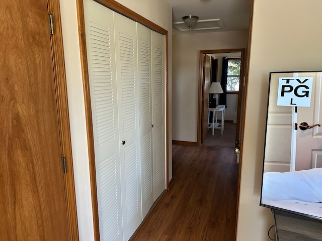 hallway with attic access, dark wood-type flooring, and baseboards