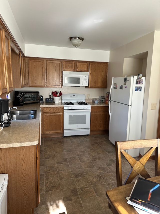 kitchen with a sink, white appliances, brown cabinets, and light countertops