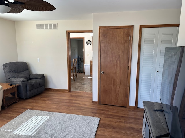 sitting room with ceiling fan, visible vents, baseboards, and wood finished floors