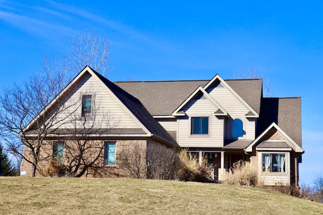 view of front of house featuring a front yard and a shingled roof