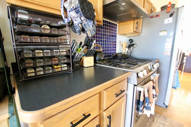 kitchen featuring light wood finished floors, tasteful backsplash, under cabinet range hood, light brown cabinetry, and stainless steel appliances