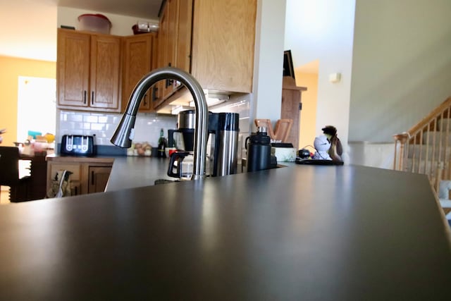 kitchen with brown cabinetry, decorative backsplash, and dark countertops