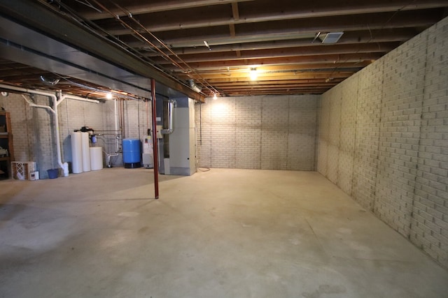 unfinished below grade area featuring heating unit and brick wall