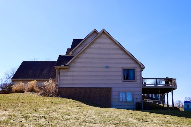 view of home's exterior featuring a wooden deck, a lawn, and brick siding