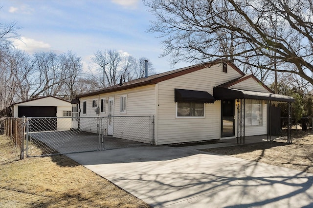 view of front facade featuring an outbuilding, a detached garage, fence, and a gate