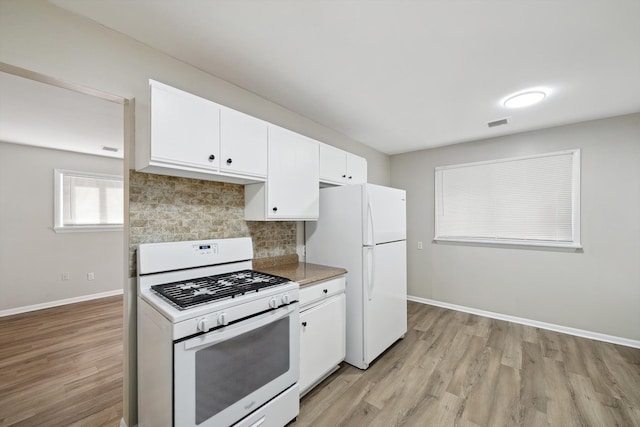 kitchen featuring white appliances, white cabinets, light wood finished floors, and decorative backsplash