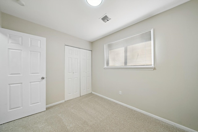 unfurnished bedroom with carpet, a closet, visible vents, and baseboards