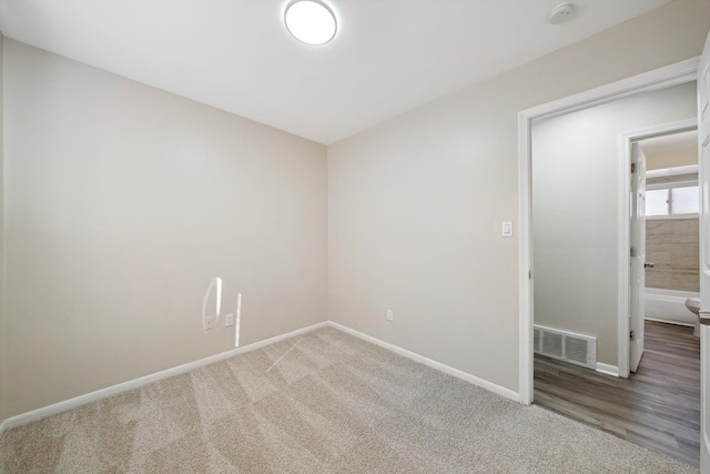 spare room with carpet floors, baseboards, and visible vents