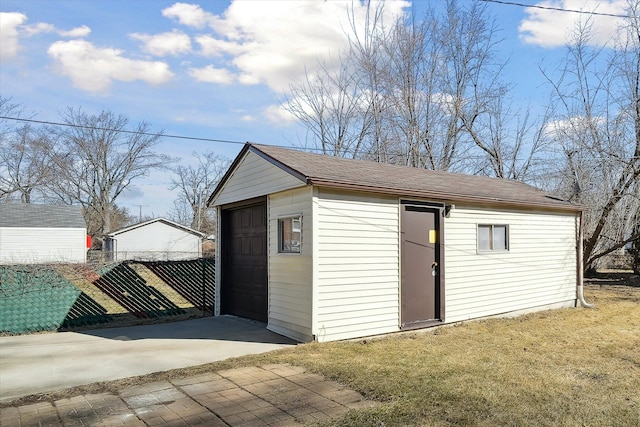 view of outbuilding with an outbuilding, fence, and driveway