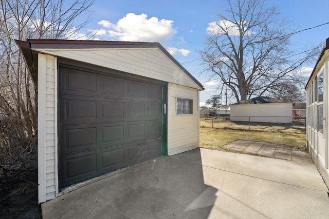 detached garage featuring driveway and fence