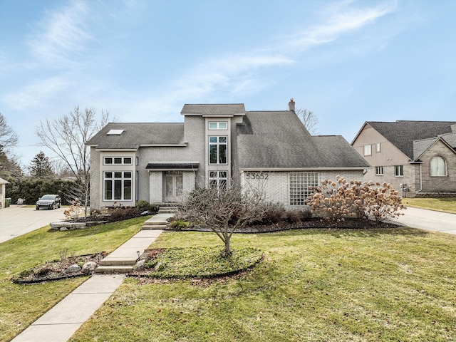 view of front of house with driveway, a chimney, a front lawn, and brick siding