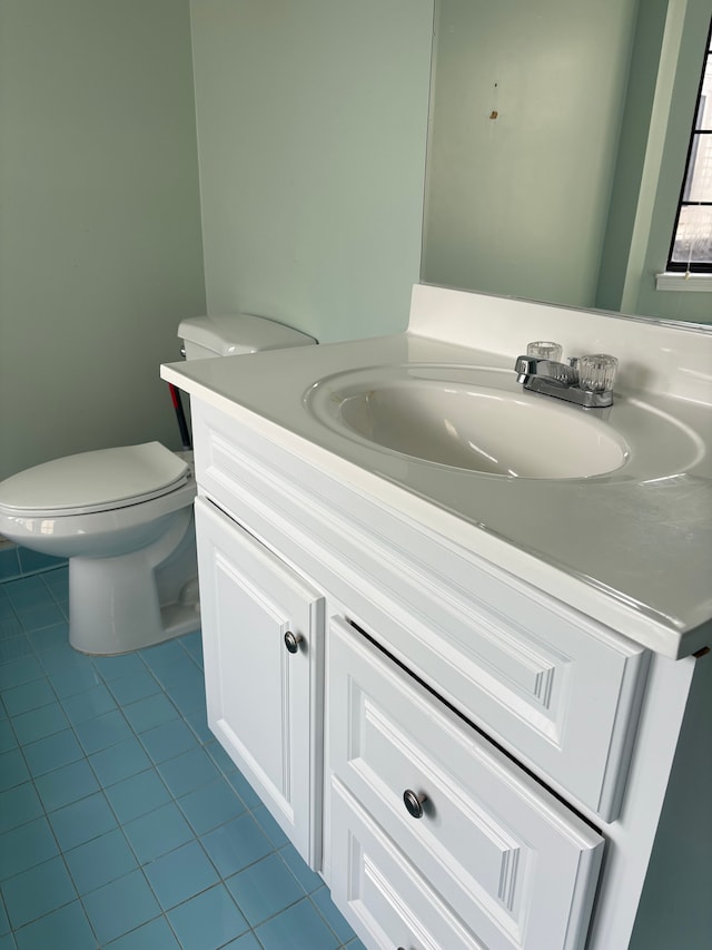 bathroom with toilet, vanity, and tile patterned flooring