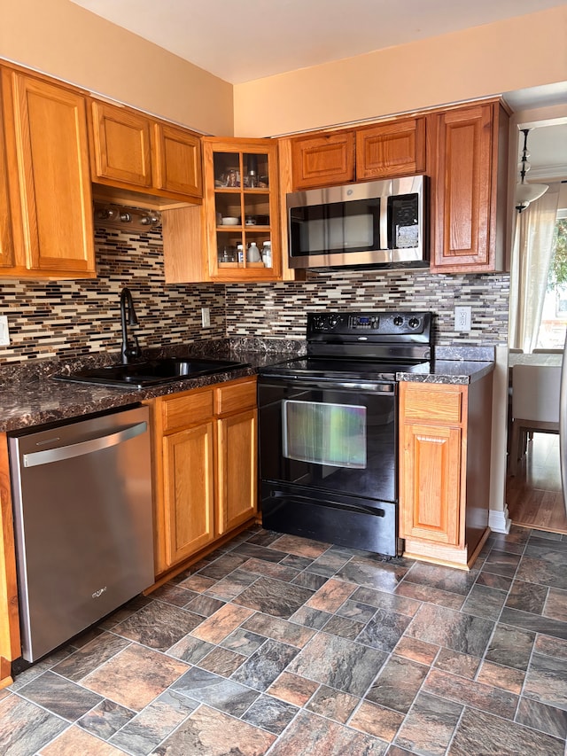 kitchen featuring a sink, stainless steel appliances, tasteful backsplash, and stone finish flooring