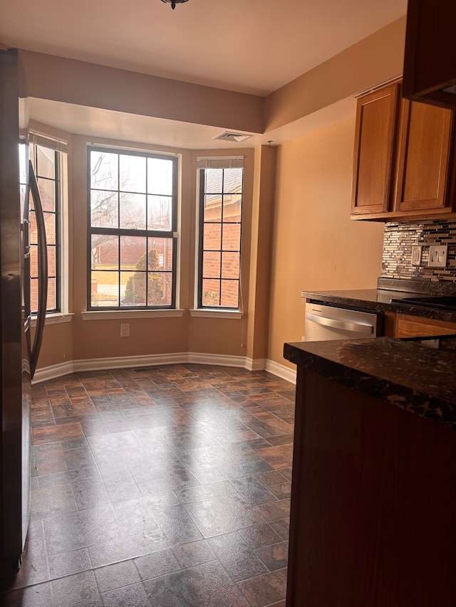 unfurnished dining area featuring visible vents, stone finish floor, and baseboards