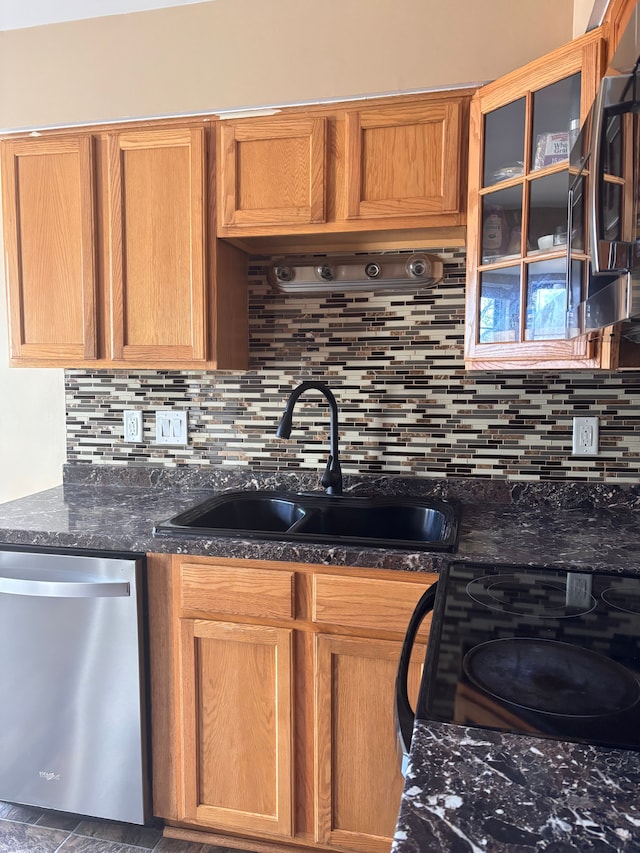 kitchen featuring a sink, stainless steel appliances, glass insert cabinets, and decorative backsplash