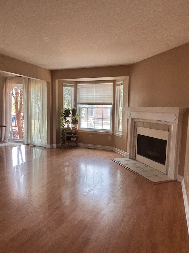 unfurnished living room with wood finished floors, a healthy amount of sunlight, and baseboards