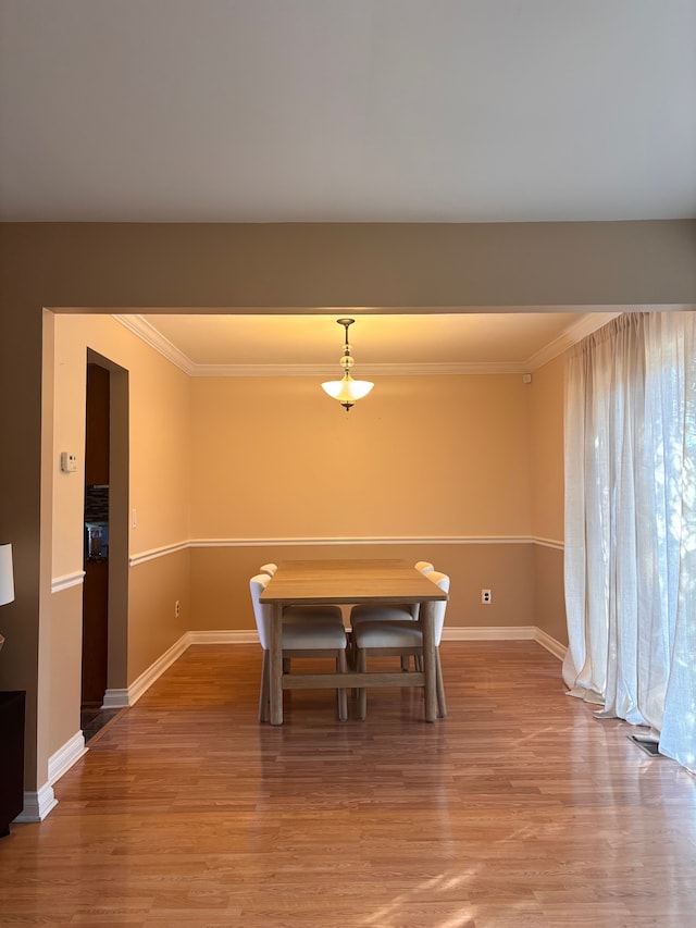 unfurnished dining area with baseboards, light wood-style flooring, and crown molding