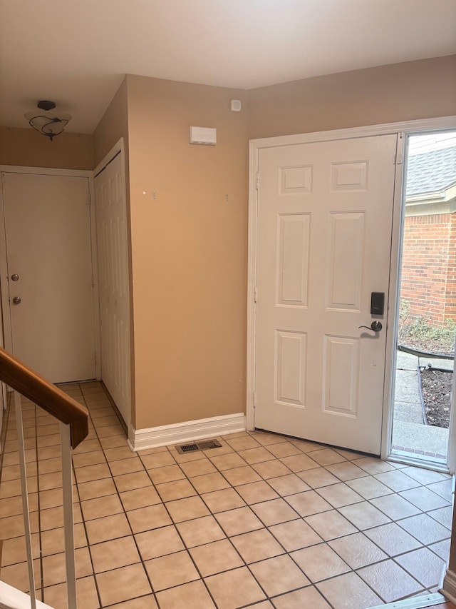 foyer entrance with light tile patterned flooring, visible vents, and baseboards