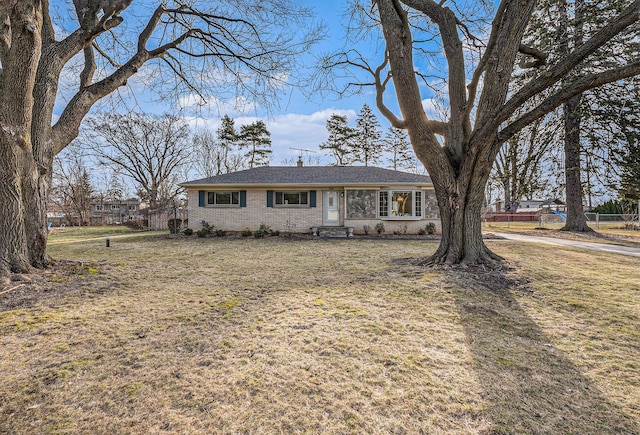 ranch-style house with a front yard, fence, and brick siding