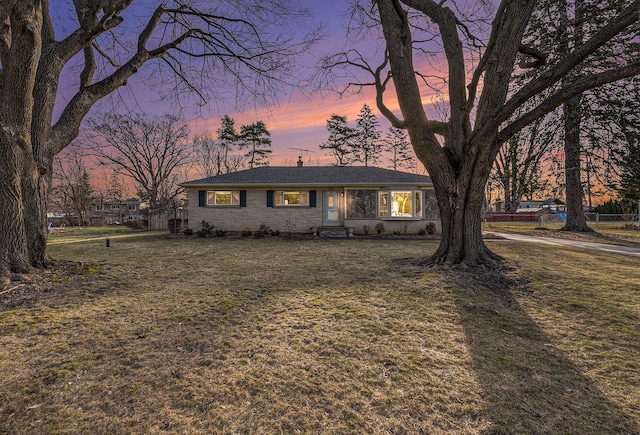 ranch-style home featuring brick siding and a front lawn