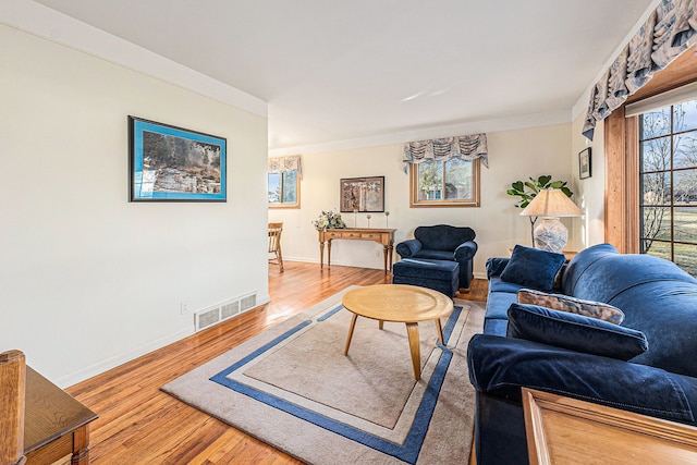 living area featuring visible vents, plenty of natural light, baseboards, and wood finished floors