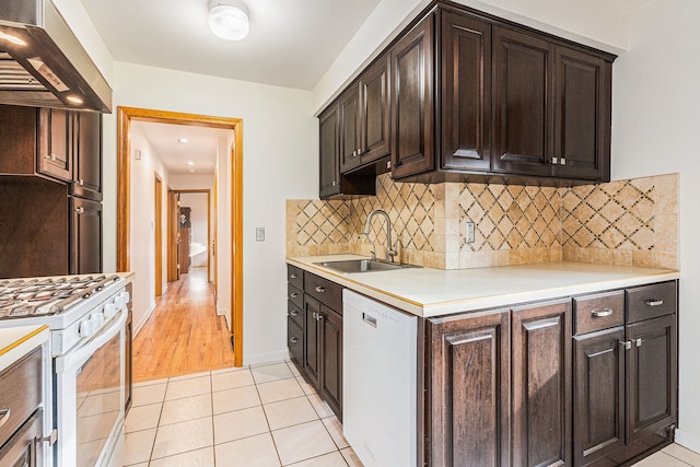 kitchen featuring dark brown cabinetry, light tile patterned floors, range hood, white appliances, and a sink