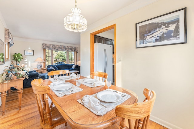 dining area with baseboards, light wood finished floors, and a chandelier