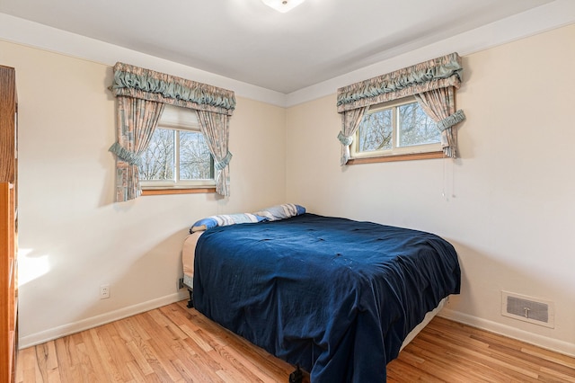 bedroom featuring multiple windows, wood finished floors, visible vents, and baseboards