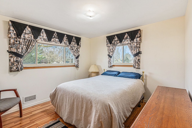 bedroom featuring visible vents, baseboards, and wood finished floors