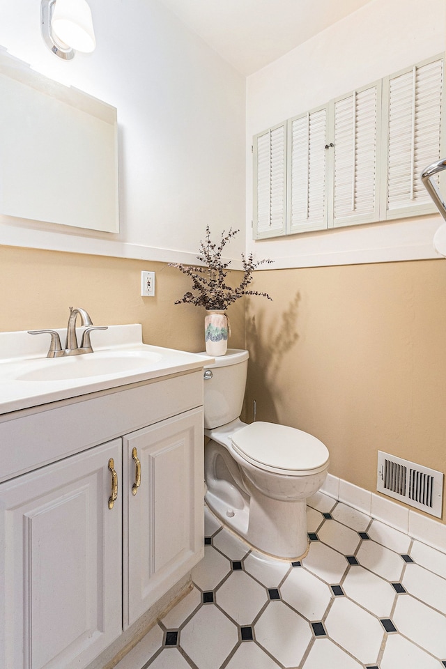 half bathroom featuring vanity, tile patterned floors, toilet, and visible vents