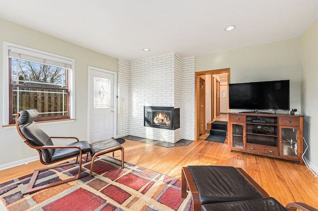 living area with light wood-style flooring, recessed lighting, a fireplace, and baseboards