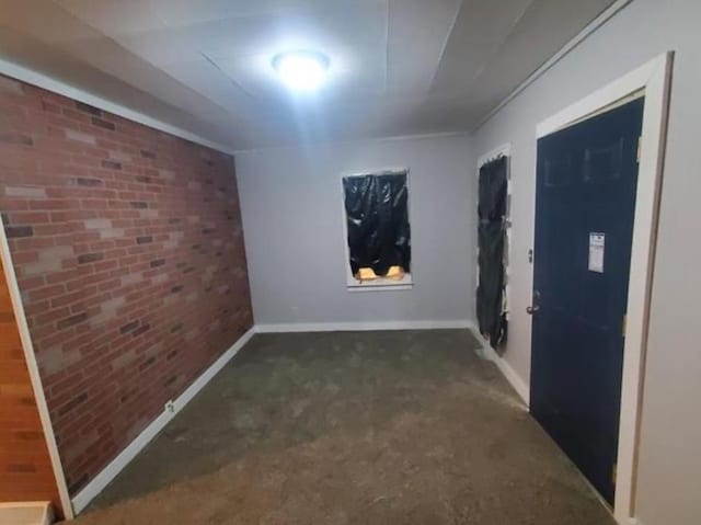 empty room featuring brick wall and baseboards