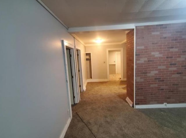 hall featuring brick wall, carpet flooring, and baseboards