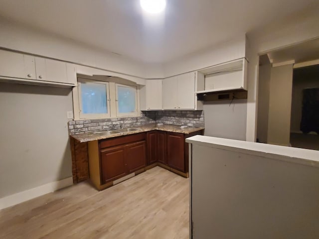 kitchen featuring white cabinets, a sink, light wood finished floors, and decorative backsplash