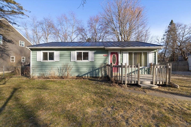 view of front of home featuring metal roof, a standing seam roof, a front lawn, and fence