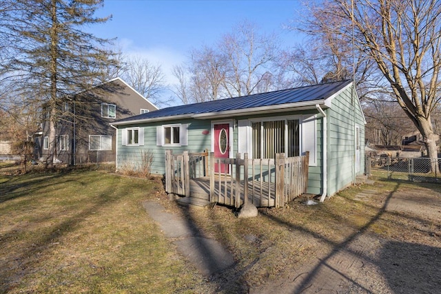 view of front of property featuring metal roof, a front yard, and fence