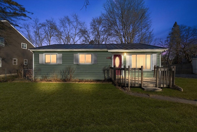 view of front of property featuring a standing seam roof, a yard, fence, and metal roof