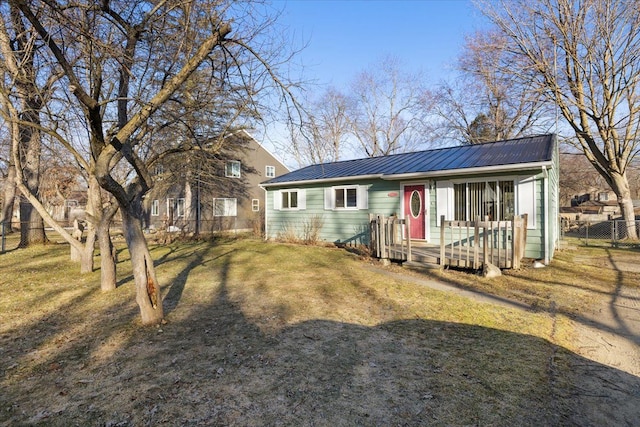 ranch-style home with a standing seam roof, metal roof, a front yard, and fence