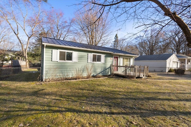 view of front facade with metal roof, a deck, a front lawn, and fence