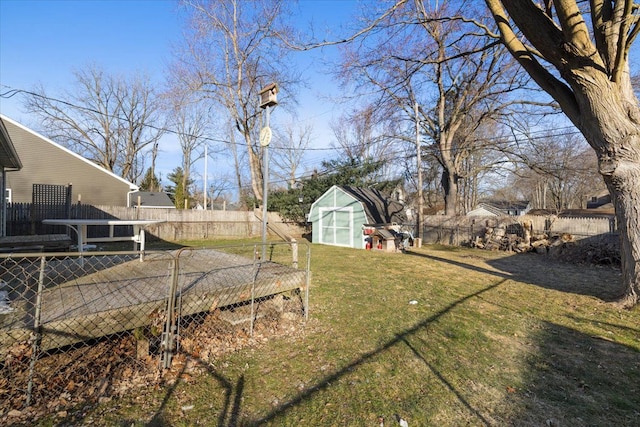 view of yard featuring a storage unit, an outdoor structure, and fence