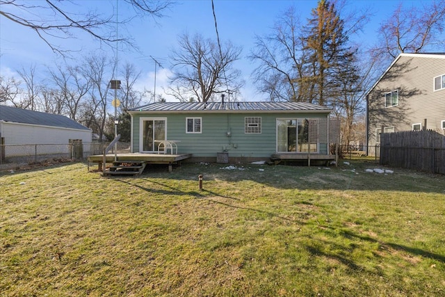 back of house with a fenced backyard, a lawn, metal roof, and a deck