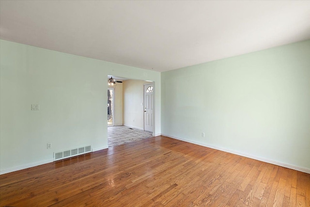 empty room featuring visible vents, baseboards, and wood finished floors