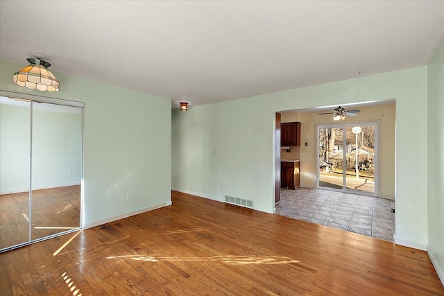 interior space featuring visible vents, a ceiling fan, baseboards, and wood finished floors